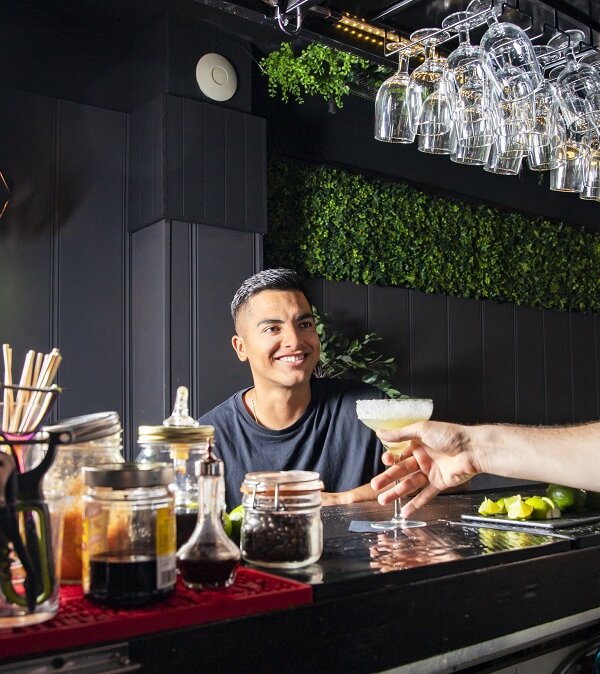 a Latin American customer at a bar receives a drink from the waiter. horizontal