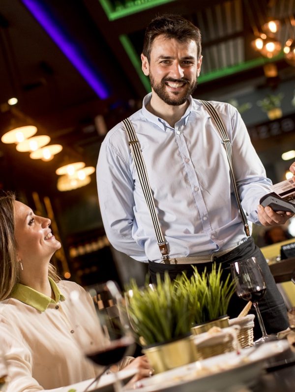 Young man paying with contactless credit card in the restaurant after dinner