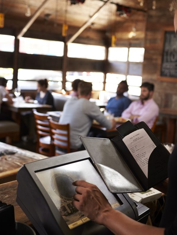 Young woman preparing bill at restaurant using touch screen